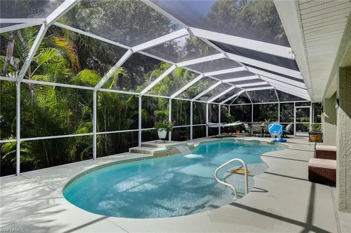 Swimming pool featuring a lanai, a sunroom, a patio, and view of scattered trees