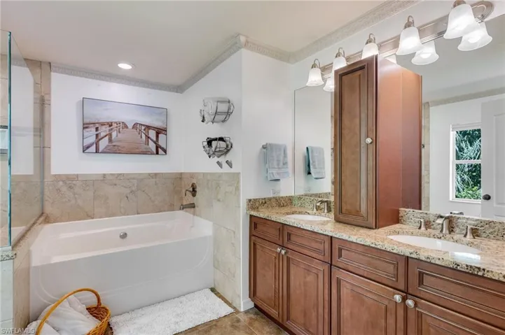 Bathroom with a garden tub, double vanity, ornamental molding, light tile patterned floors, and recessed lighting
