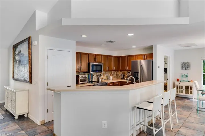 Kitchen featuring stainless steel appliances, an island with sink, recessed lighting, backsplash, and a breakfast bar area