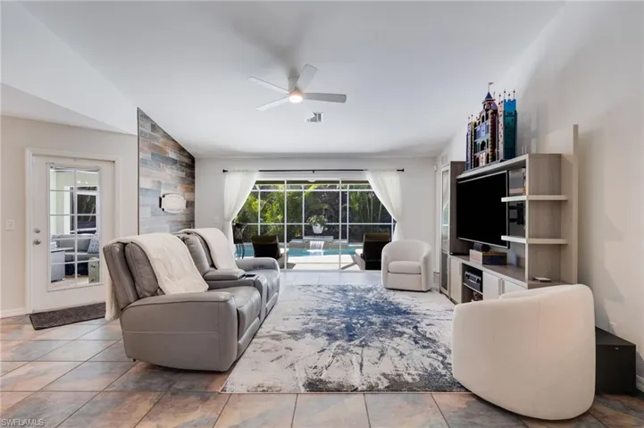 Living room with ceiling fan, a sunroom, and lofted ceiling