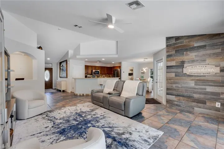 Living room with wood walls, ceiling fan, recessed lighting, and vaulted ceiling