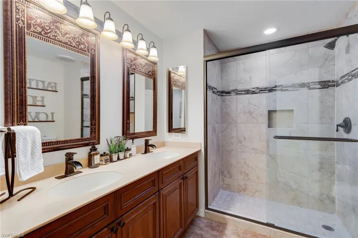 Full bathroom with double vanity, a shower stall, and light tile patterned floors