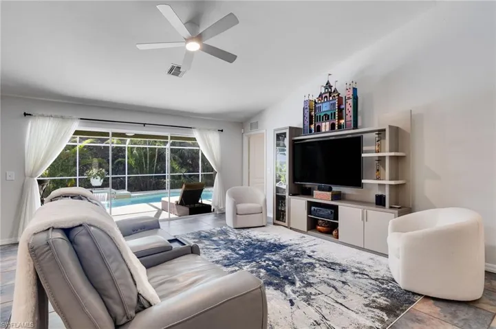Tiled living area featuring vaulted ceiling, a ceiling fan, and a sunroom