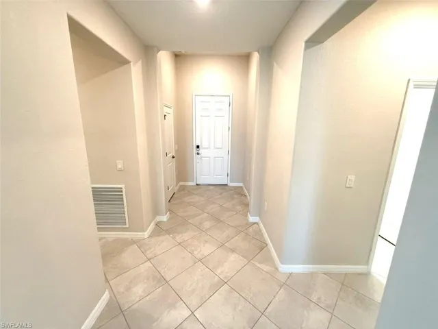 Hallway featuring baseboards and light tile patterned floors