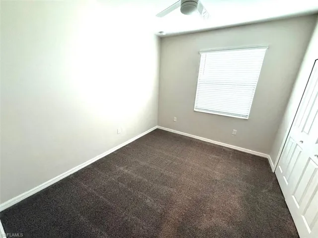 Unfurnished bedroom with dark colored carpet, a closet, and ceiling fan