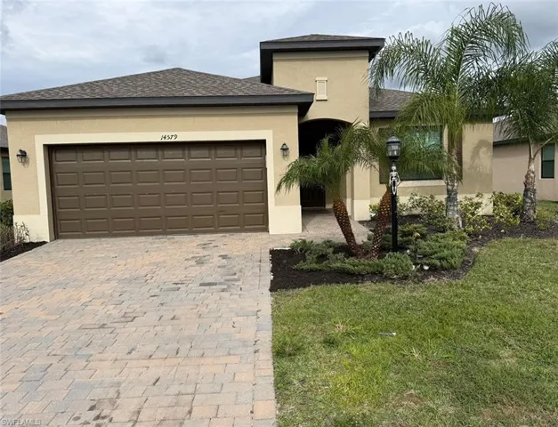 View of front of home featuring stucco siding, decorative driveway, a shingled roof, a front yard, and an attached garage