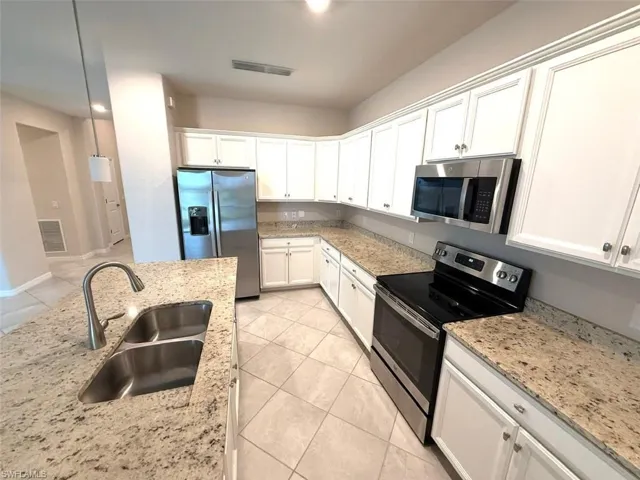 Kitchen featuring stainless steel appliances, white cabinets, light tile patterned floors, and recessed lighting