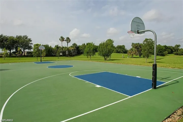 View of basketball court featuring community basketball court, a yard, and view of wooded area