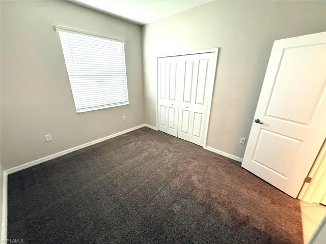 Unfurnished bedroom with dark colored carpet and a closet