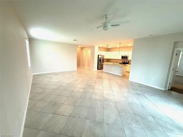 Unfurnished living room with a ceiling fan and baseboards