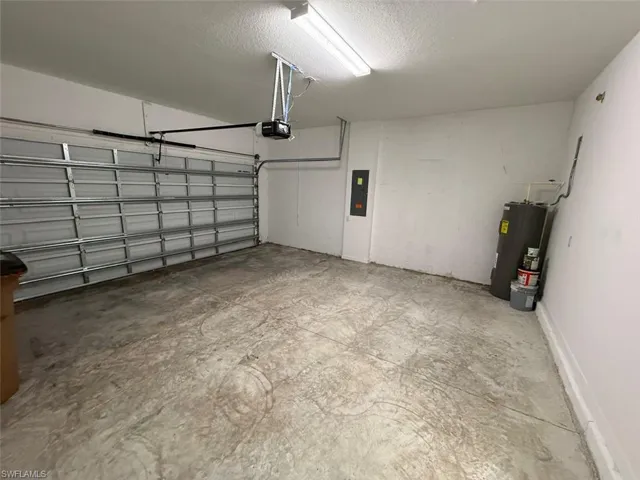 Garage featuring water heater, electric panel, and a garage door opener