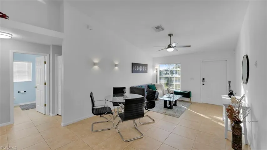Tiled dining room with ceiling fan and high vaulted ceiling