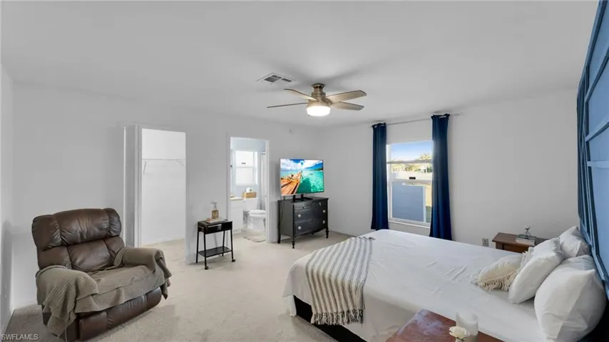 Bedroom with ensuite bath, ceiling fan, a spacious closet, light colored carpet, and a closet