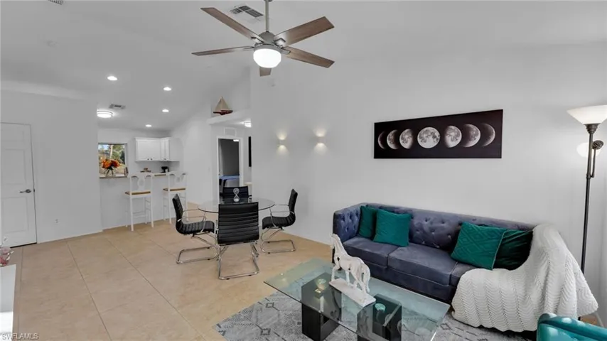 Tiled living room with lofted ceiling and ceiling fan