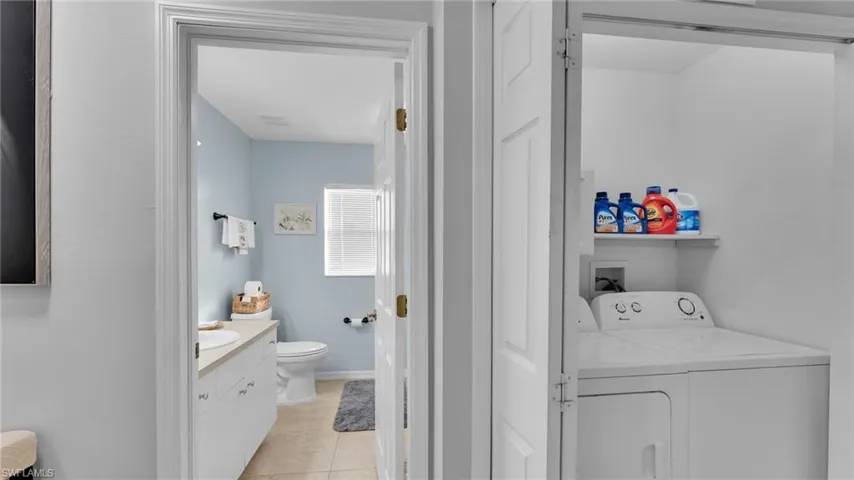 Washroom featuring separate washer and dryer, sink, and light tile patterned floors