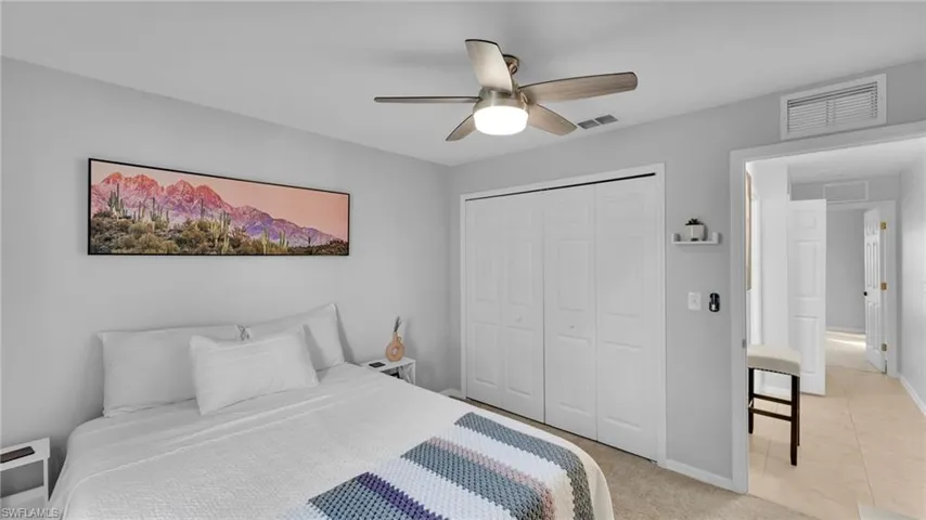 Bedroom with light colored carpet, ceiling fan, and a closet
