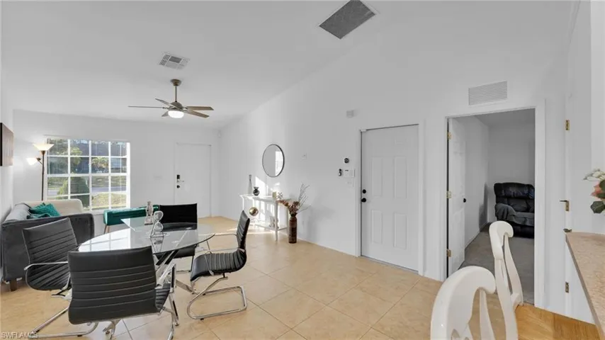 Dining space with light tile patterned floors, vaulted ceiling, and ceiling fan