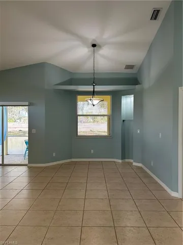 Unfurnished dining area featuring light tile patterned floors and lofted ceiling