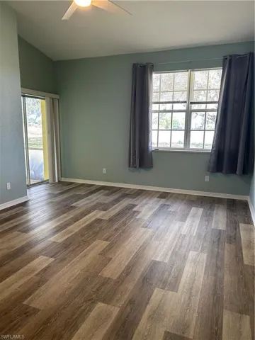 Empty room featuring dark wood-type flooring, ceiling fan, and lofted ceiling
