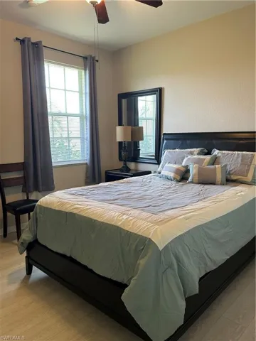 Bedroom featuring light wood-style flooring, ceiling fan, and multiple windows.  Furniture can stay with the home or owner is happy to remove.