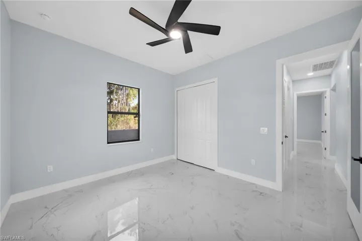 Unfurnished bedroom featuring a ceiling fan, light marble finish floors, and a closet