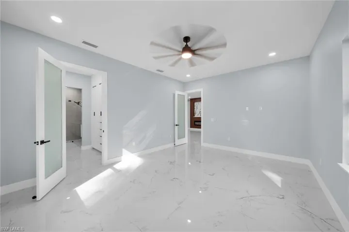 Unfurnished bedroom featuring recessed lighting, a ceiling fan, connected bathroom, and french doors