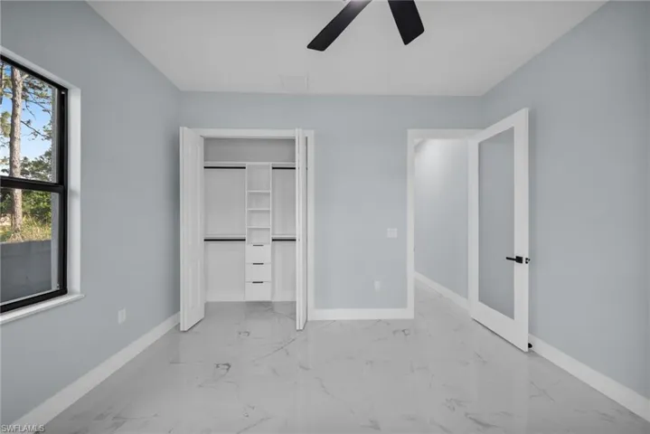 Unfurnished bedroom with a ceiling fan, a closet, and light marble finish flooring