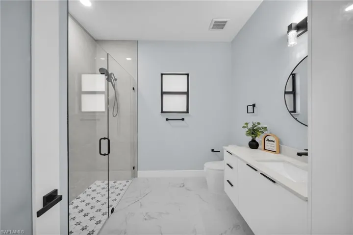 Full bath with vanity, a shower stall, light marble finish flooring, and recessed lighting