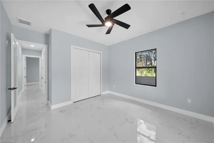 Unfurnished bedroom with a closet, a ceiling fan, and light marble finish floors