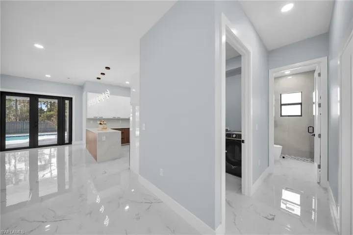 Hallway with french doors, recessed lighting, light marble finish floors, and washer / clothes dryer