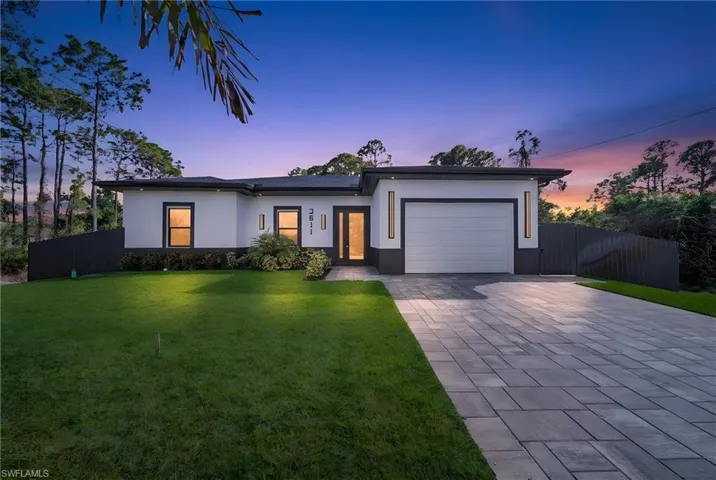 View of front of house with an attached garage, driveway, and stucco siding