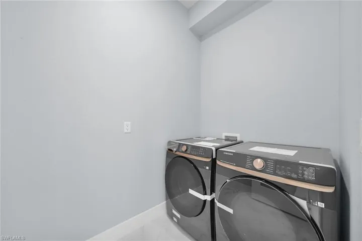 Laundry area featuring independent washer and dryer and marble finish floors