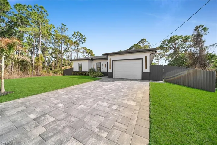 View of front of property with a gate, a garage, driveway, and stucco siding