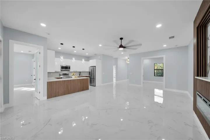 Kitchen featuring open floor plan, light countertops, white cabinetry, a ceiling fan, and stainless steel appliances