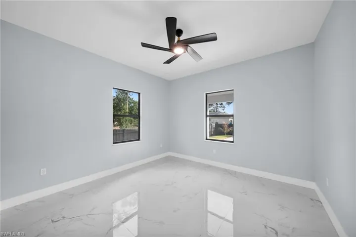 Unfurnished room with light marble finish floors and ceiling fan