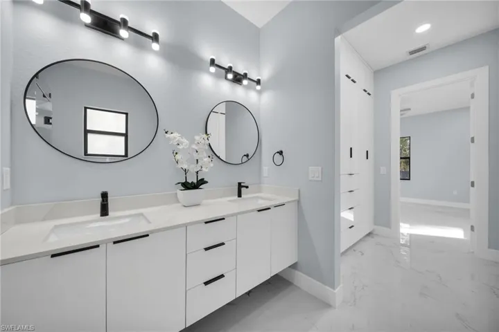 Bathroom featuring double vanity and light marble finish floors