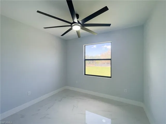 Unfurnished room with a ceiling fan and light marble finish floors