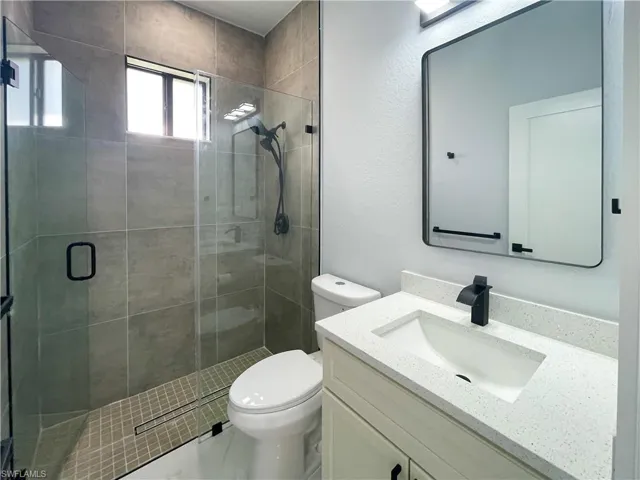 Bathroom with vanity, a stall shower, and a textured wall