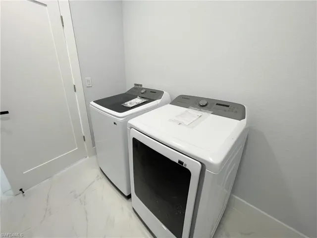Laundry area with washing machine and clothes dryer and light marble finish floors