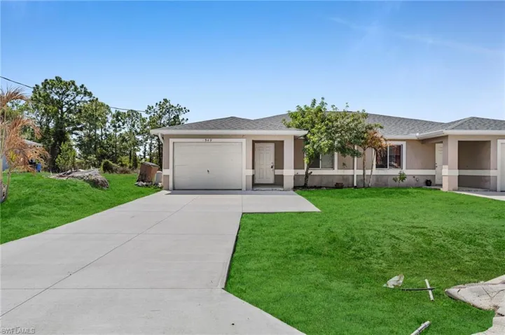 Single story home featuring a front yard, stucco siding, concrete driveway, a shingled roof, and a garage
