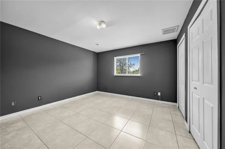 Unfurnished bedroom featuring light tile patterned floors and two closets