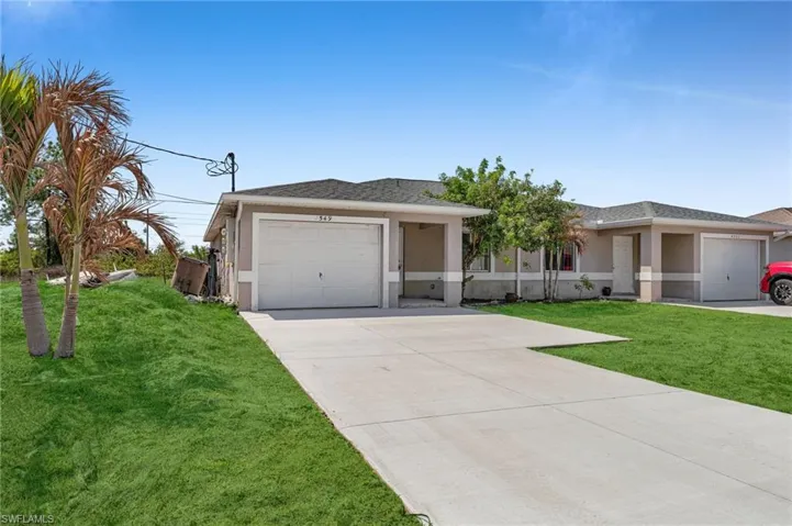View of front of property with a front lawn, driveway, stucco siding, and a shingled roof