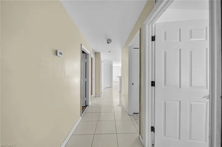 Corridor featuring light tile patterned floors and baseboards