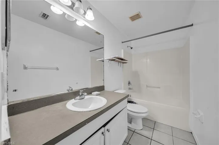 Full bath featuring vanity, washtub / shower combination, and light tile patterned flooring