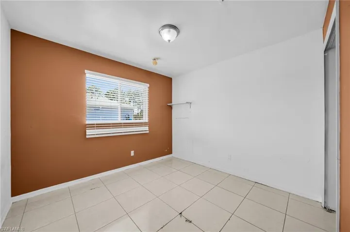 Empty room with light tile patterned flooring and baseboards