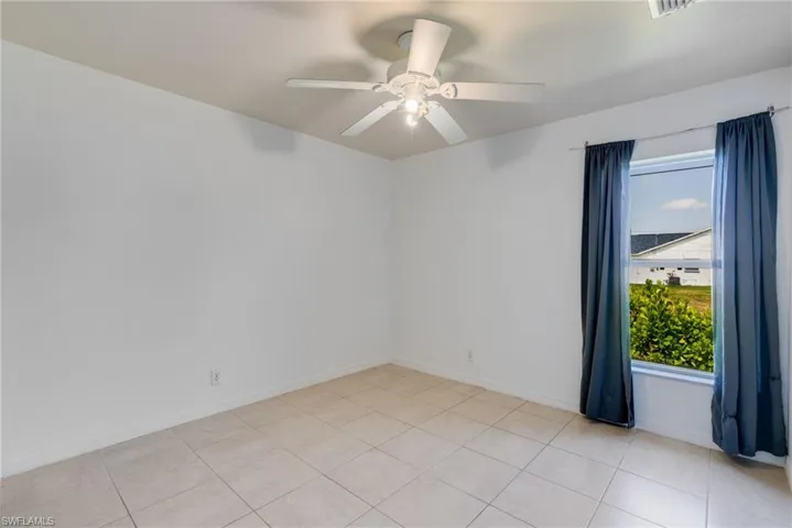 Bright interior space featuring light-toned tile flooring, white walls, and a ceiling fan with integrated lighting
