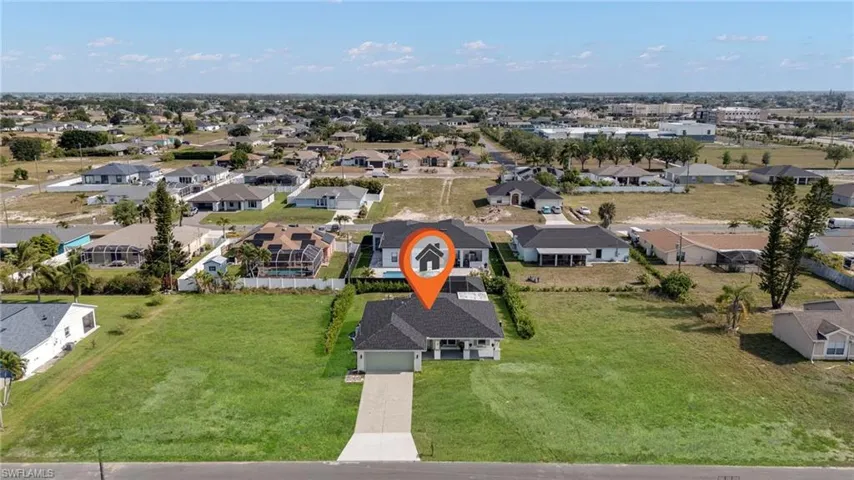 Aerial perspective highlighting a single-story residence with a gray shingled roof, a paved driveway, and an attached garage