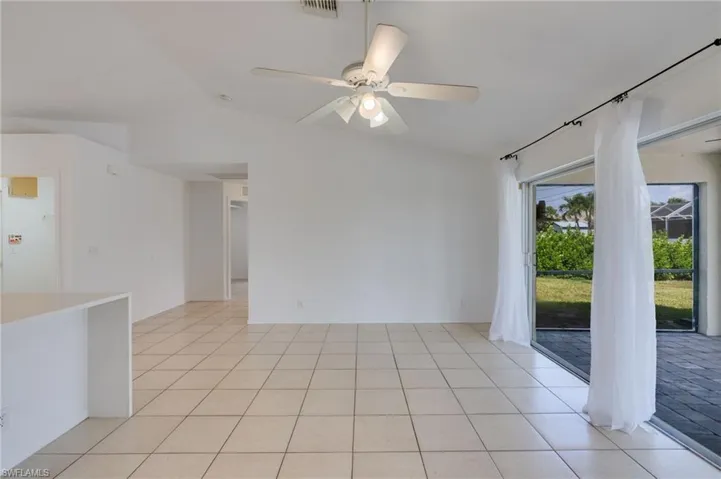 Open-concept interior featuring light-colored tile flooring, vaulted ceilings, and a ceiling fan