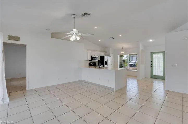 Expansive open-concept room featuring tile flooring, vaulted ceilings, and recessed lighting