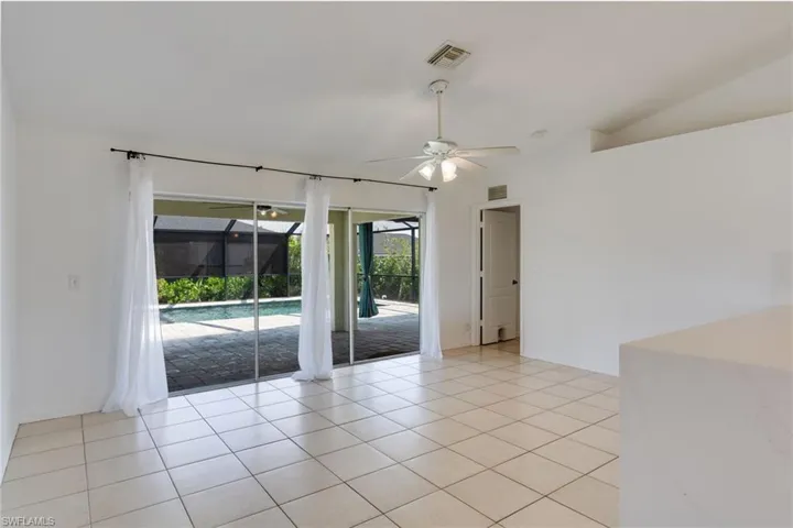 Bright interior room featuring light-toned tile flooring, direct access to a screened-in patio, and an outdoor swimming pool